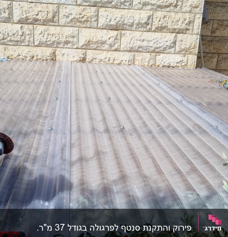 כלי עבודה על גג פלסטיק שקוף ליד קיר אבן